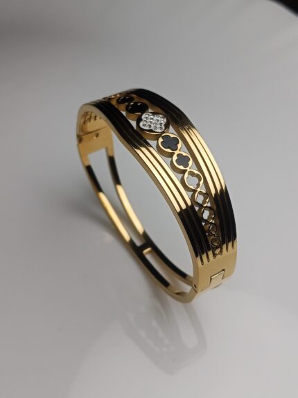 Introduce a touch of sophisticated glamour to your collection with this stunning 24K Gold Plated Roman Numeral Bangle. This contemporary classic seamlessly blends luxurious design with everyday durability. The high-shine gold plating highlights the intricately engraved Roman numerals, which are beautifully accented by a continuous row of sparkling pave crystals along the edge, catching the light with every movement. Designed with a secure, hinged closure, this bracelet is easy to wear and stays comfortably in place. Crafted from premium stainless steel, it promises long-lasting shine and resistance to tarnish, making it the perfect statement piece for any occasion—from a casual brunch to a formal evening event. Key Features: Premium Material: Durable and tarnish-resistant stainless steel base. Luxe Finish: Rich, high-quality 24K gold plating for a lasting, brilliant shine. Elegant Design: Engraved with iconic Roman numerals for a sophisticated, classic look. Sparkling Accents: Adorned with a continuous line of brilliant pave crystals. Comfort & Fit: Features a secure hinged closure for easy on-and-off. Perfect Gift: An ideal gift for birthdays, anniversaries, or special occasions. Style: Stackable design—perfect for layering with other bracelets or wearing solo as a statement piece.